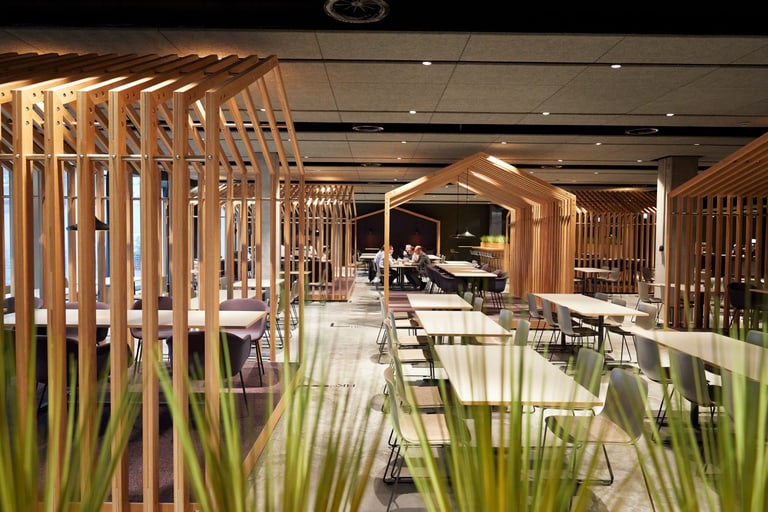 Stylisches und modernes Restaurant mit vielen Tischen und durch Holzlamellen voneinander getrennten Sitzbereichen.