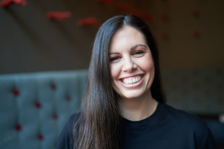 Frau mit langen Haaren lächelt in Innenraum.