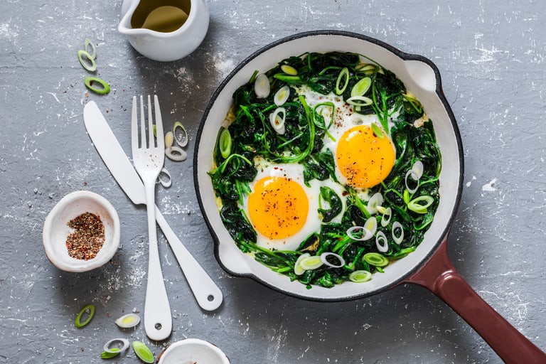 Grüne Shakshuka mit Ei, Spinat, Bärlauch in einer Pfanne schön angerichtet.