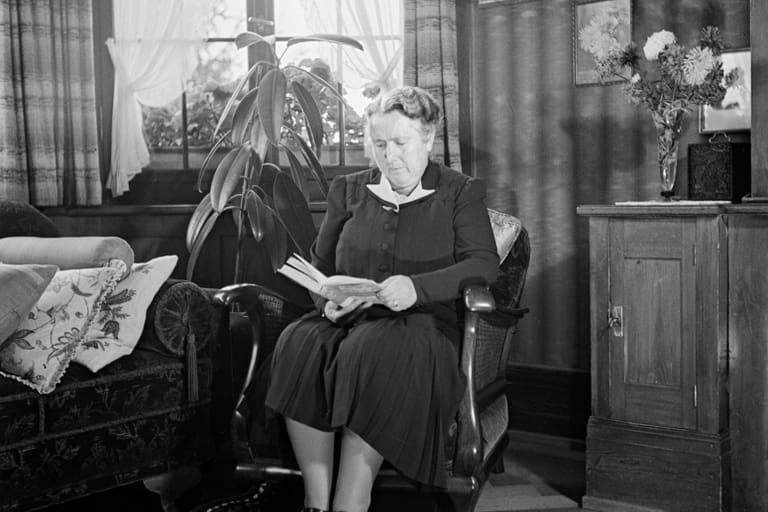 Historisches Bild von der Gründerin der SV Else Züblin-Spiller, die auf einem Stuhl im Wohnzimmer sitzt und ein Buch liest.