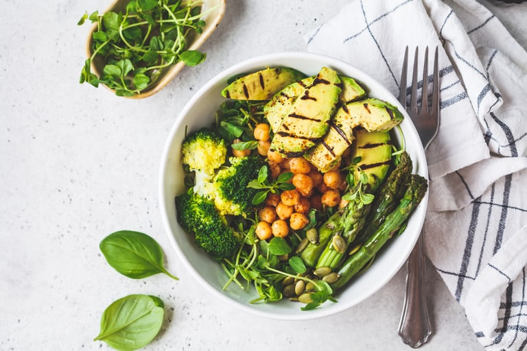 Gesunde Bowl mit Kichererbsen, Spargeln, Broccoli und Avocado.