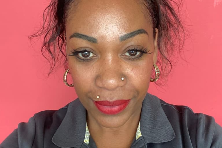 Porträt einer Frau vor rosa Hintergrund mit Namensschild.