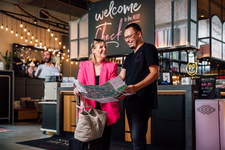 Zwei Menschen schauen auf eine Karte in einer Hotellobby mit Willkommensschild.