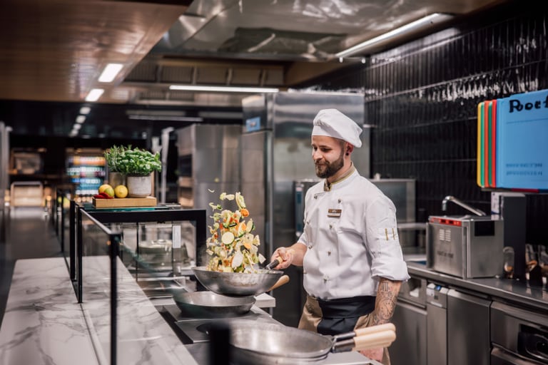 Koch in Restaurantküche wirft Gemüse in der Pfanne.