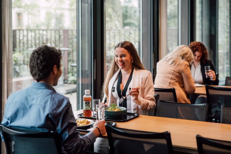 Zwei Personen essen zusammen an einem Tisch im Restaurant, zwei weitere Personen sitzen im Hintergrund.