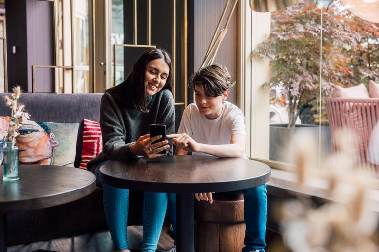 Zwei Personen, die in einem Café auf ein Smartphone schauen.