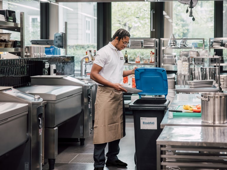 Küchenmitarbeiter bei der Müllentsorgung in einer professionellen Küche.