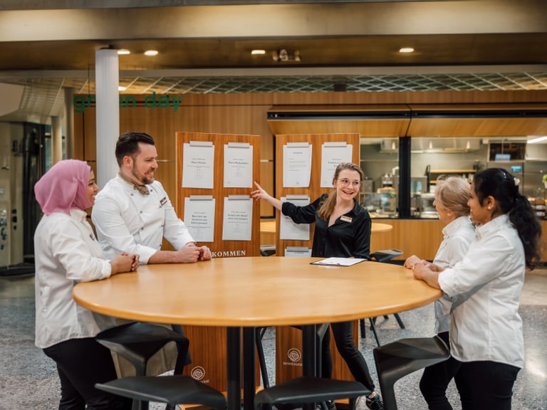 Team von Restaurantmitarbeitern bei einem Meeting am runden Tisch.