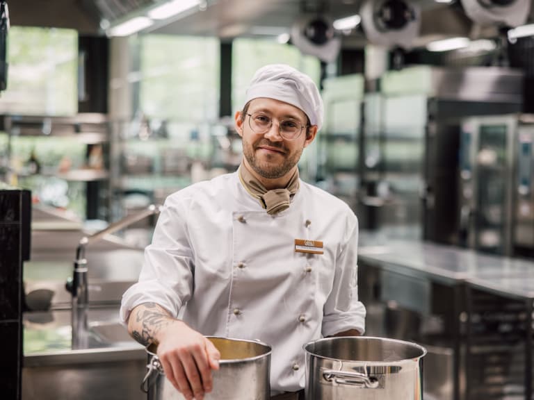 Koch in einer professionellen Küche mit Töpfen.