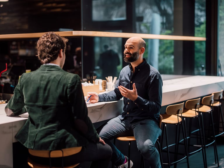Zwei Männer unterhalten sich in einer modernen Café-Bar.