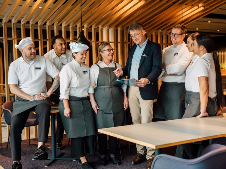Gruppe von Restaurantmitarbeitern in Uniform lächelnd mit Manager.