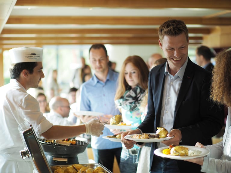 Gäste stehen am Selbstbedienungsbuffet auf dem Schiff und freuen sich über die tolle Auswahl an frischen Gerichten.