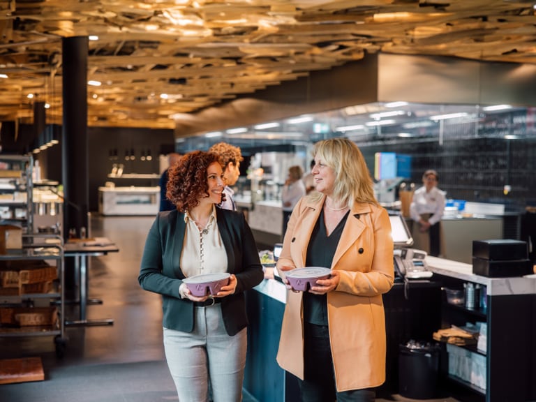 Zwei Frauen gehen in einem Restaurant mit moderner Inneneinrichtung.