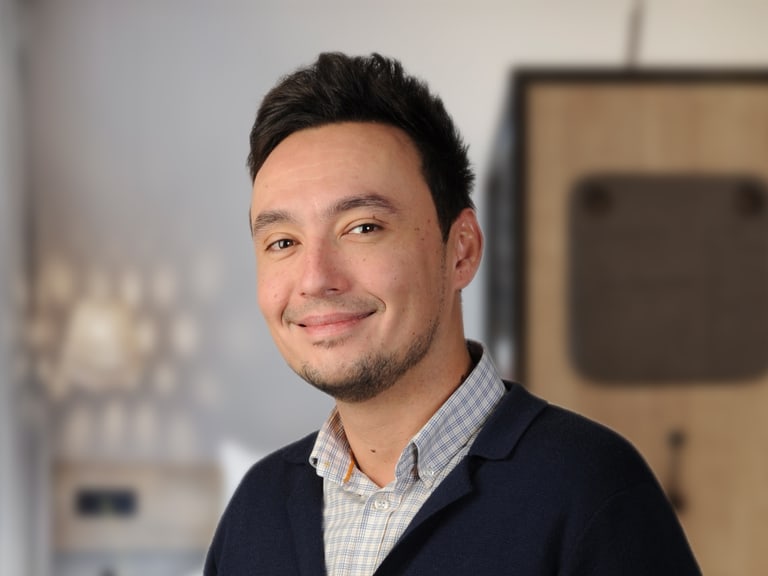 Porträt eines lächelnden Mannes in einem Büro.",