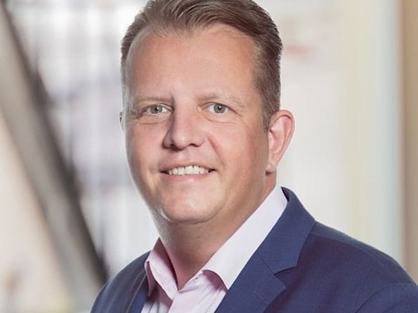 Porträt eines lächelnden Geschäftsmannes in Anzug und Krawatte in einem Büro.