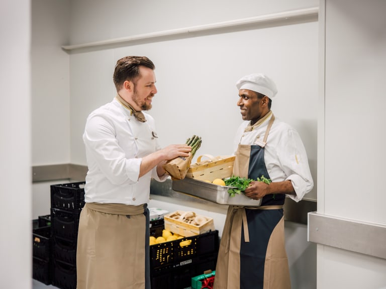 Zwei Köche in einer Küche sortieren Gemüse.