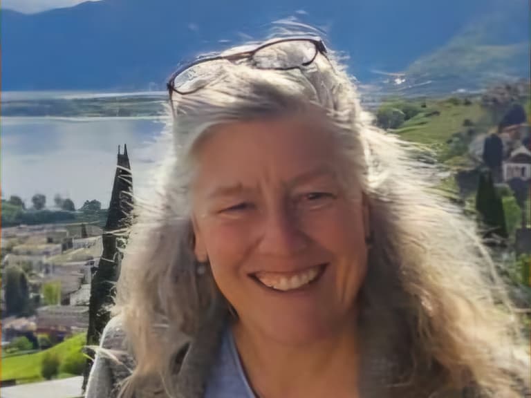 Frau lächelt vor Berg- und Seelandschaft.