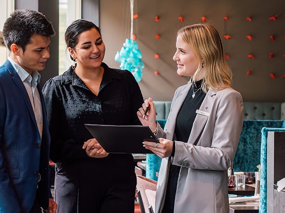 Drei Personen in einem Gespräch mit einem Klemmbrett im Restaurant.