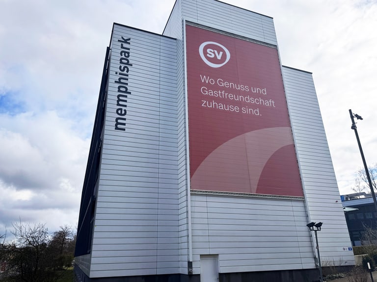 Gebäude mit SV-Logo und Schriftzug 'Wo Genuss und Gastfreundschaft zuhause sind.'