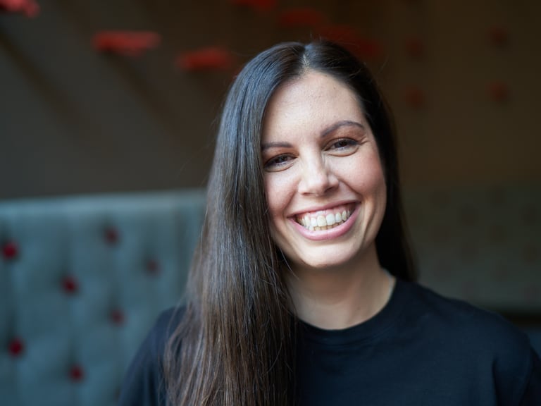 Frau mit langen Haaren lächelt in Innenraum.