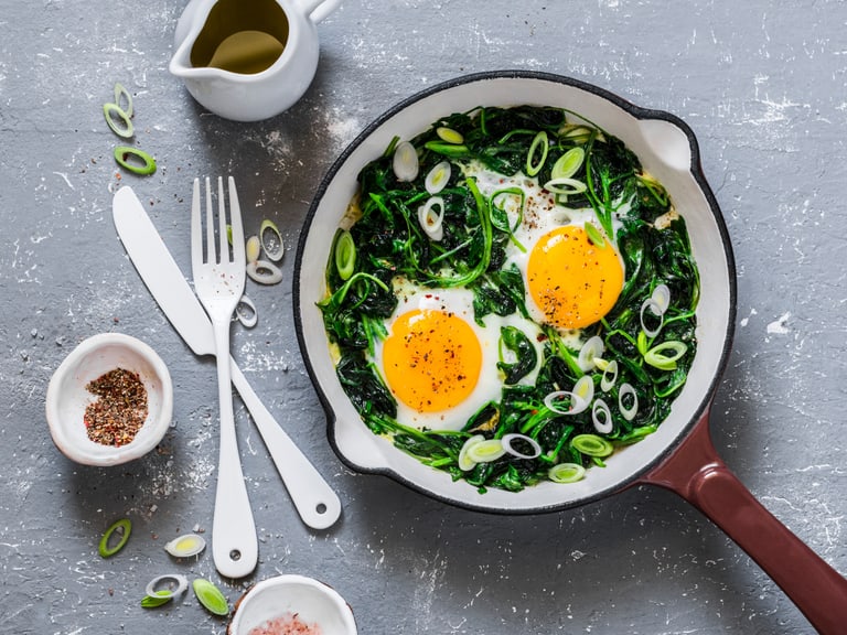 Grüne Shakshuka mit Ei, Spinat, Bärlauch in einer Pfanne schön angerichtet.