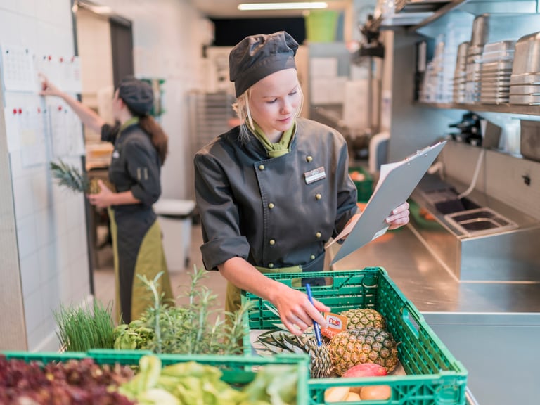 Köchin in Uniform überprüft Lebensmittellieferung in der Küche.