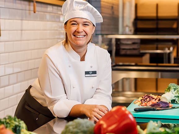 Lächelnde Köchin in der Küche mit frischem Gemüse.