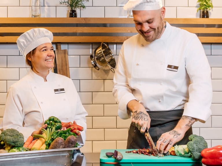 Zwei Köche schneiden Gemüse in einer Küche.