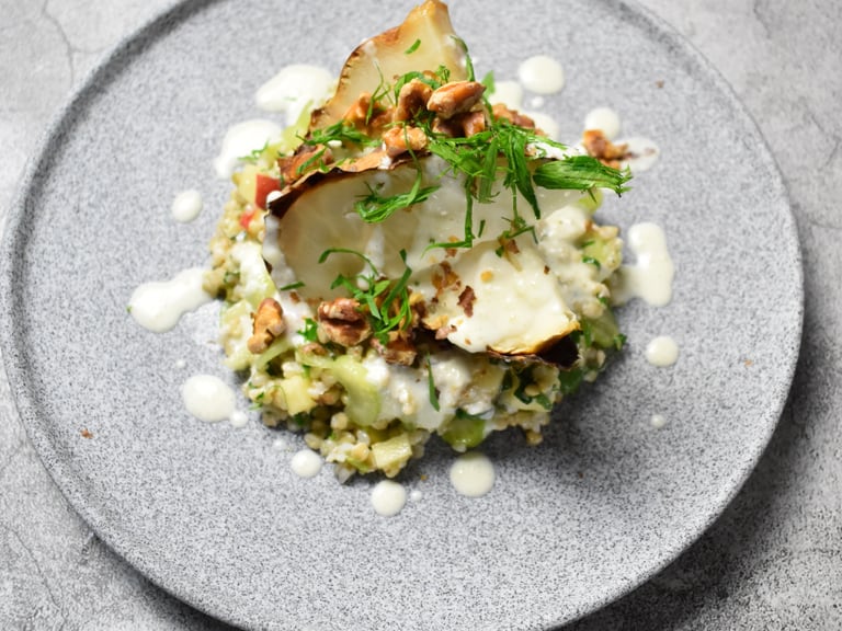 Schön auf einem Teller angerichtetes Gericht mit gebackenem Sellerie und Buchweizensalat nach den Grundlagen der Planetary Health Diet.