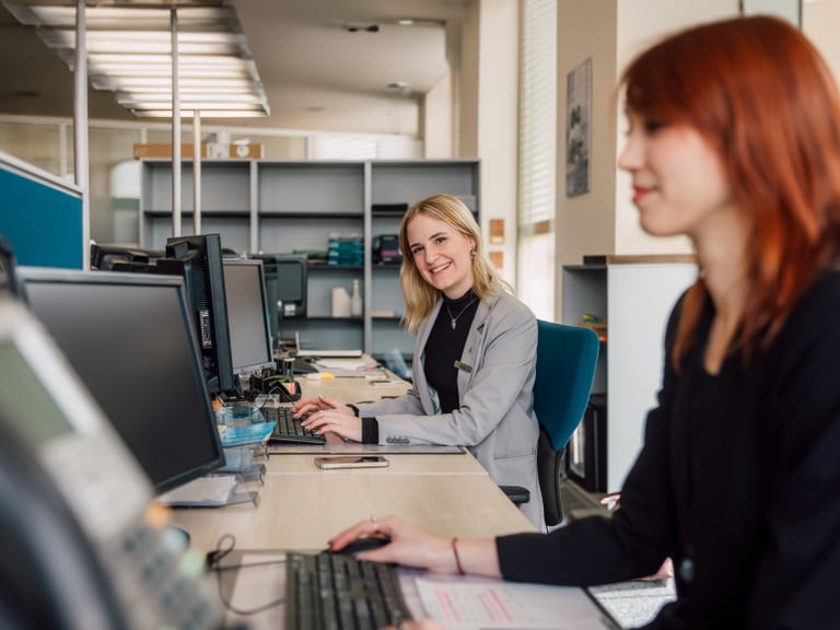 Zwei Frauen arbeiten an Computern in einem Büro.