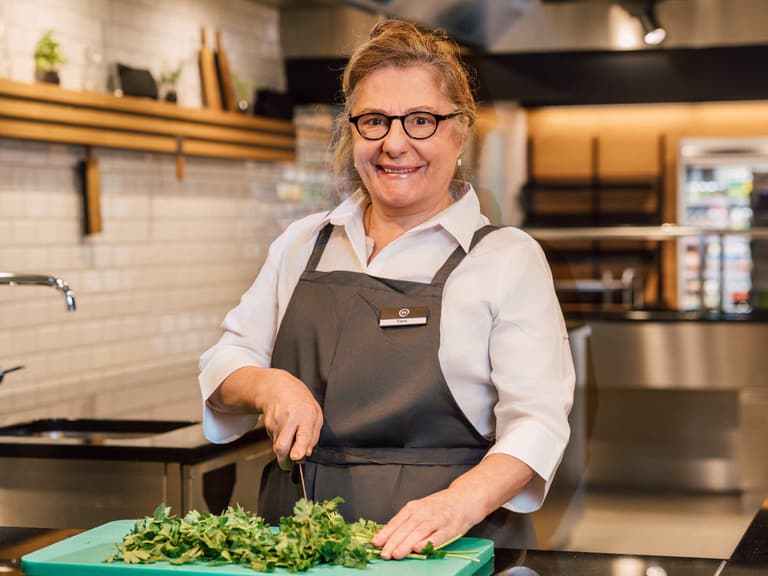 Köchin schneidet Kräuter in moderner Küche.