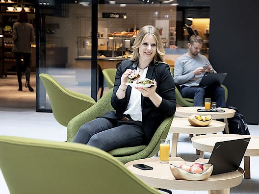 Frau sitzt in einem gemütlichen Cafe und geniesst ihr Mittagessen.