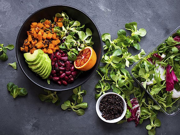Eine ausgewogene und vielfältige Salatschüssel mit Avocado, Nüsslisalat, Quinoa und roten Bohnen.