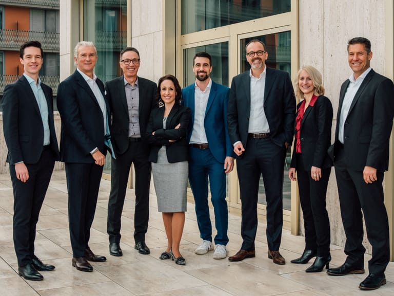 Gruppe von acht Geschäftsleuten auf einer Terrasse stehend.