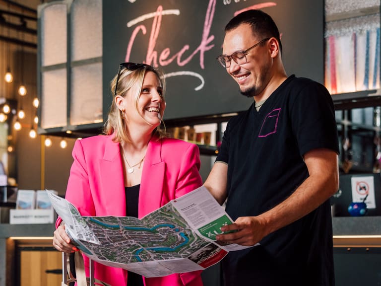 Zwei Personen mit Karte vor Rezeption des Moxy Hotels.