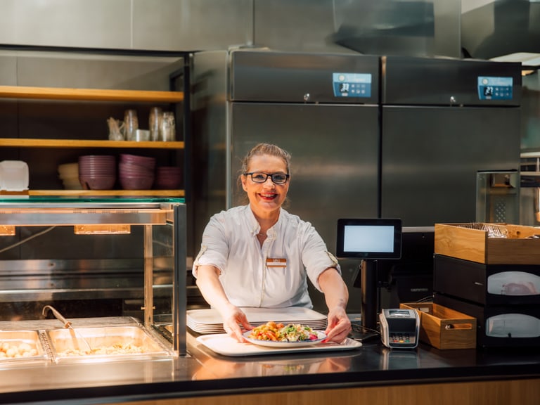 Kellnerin serviert Essen in einem Restaurant hinter dem Tresen.