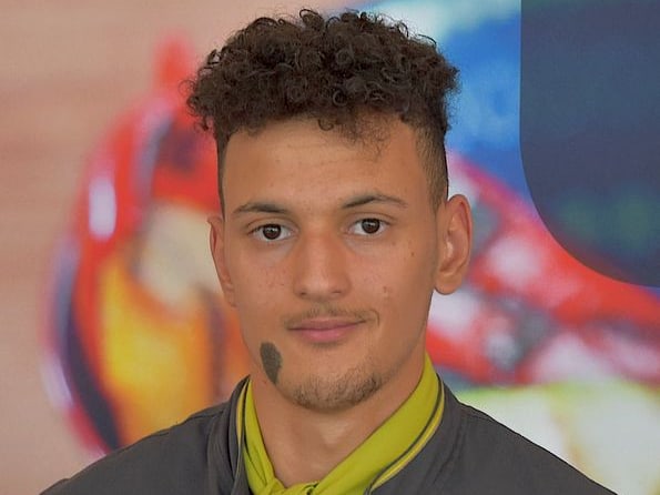 Junge Konditor in Berufskleidung vor unscharfem Hintergrund.