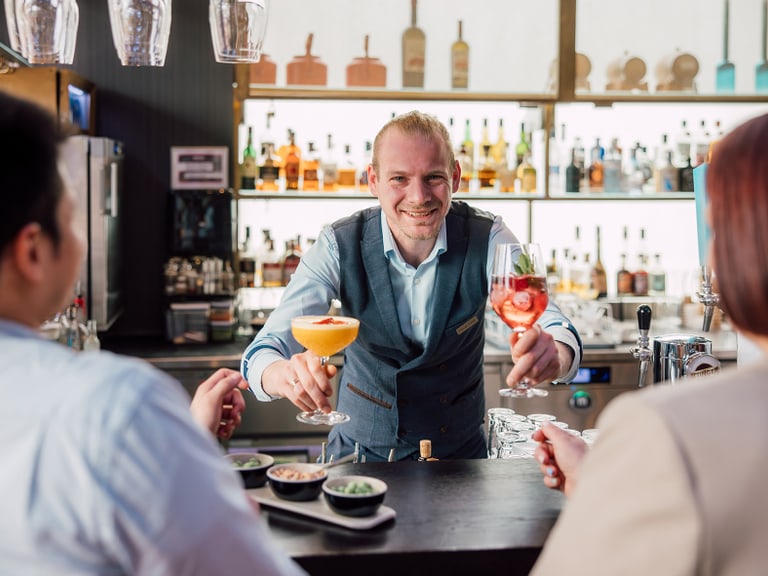 Barmann bietet Cocktails an Gäste an einer Bar an.
