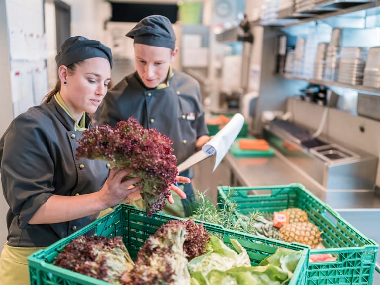 Zwei Köche sortieren frisches Gemüse in der Restaurantküche.