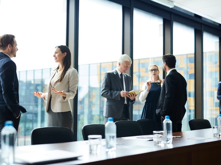 Geschäftsleute sprechen in einem Konferenzraum mit grossen Fenstern.