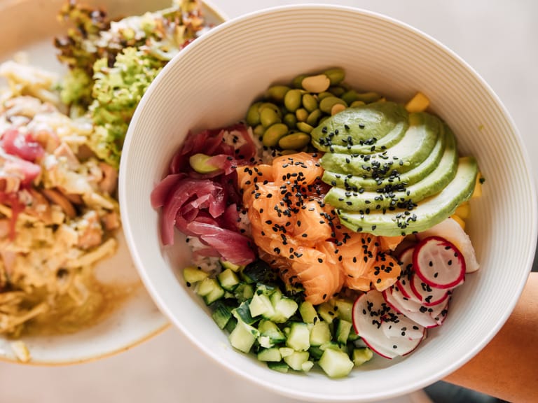 Poke Bowl mit Lachs, Avocado, Radieschen und Gemüse.