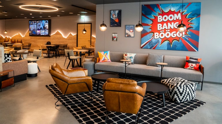 Modernes Café-Lounge mit Comics-Wandkunst und Lederstühlen.