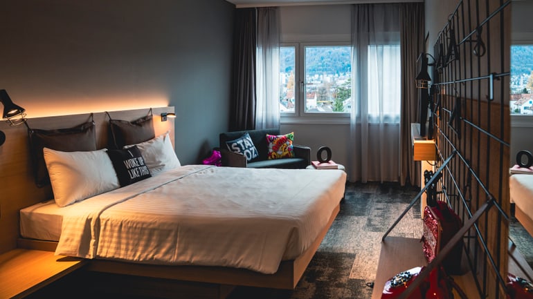 Modernes Hotelzimmer mit Doppelbett und Blick aus dem Fenster.