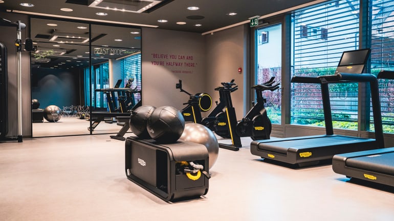 Moderner Fitnessraum mit Geräten und Spiegelwand.