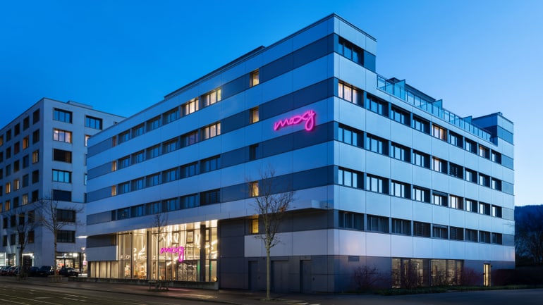 Modernes Hotelgebäude mit leuchtendem rosa Schild am Abend.