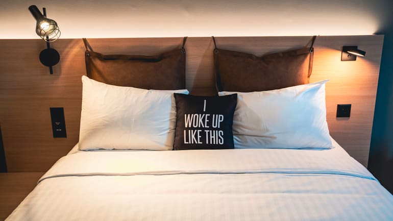 Bett mit Kissen und Schriftzug 'I woke up like this'.