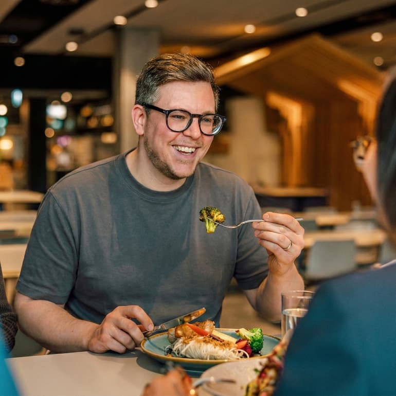 Mann lächelnd beim Essen in einem Restaurant.