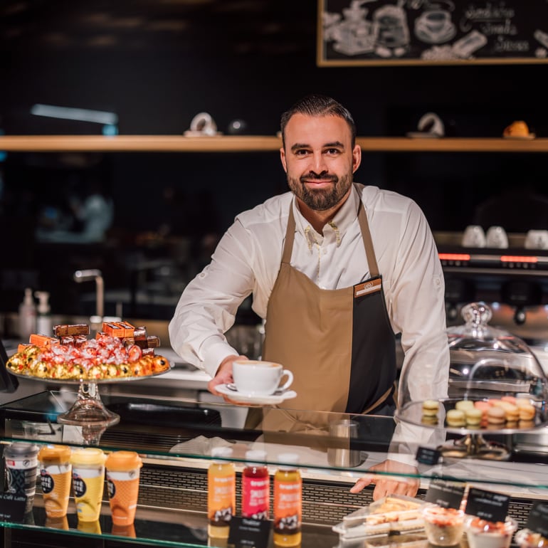 Barista bietet Kaffee an der Theke eines Cafés an.