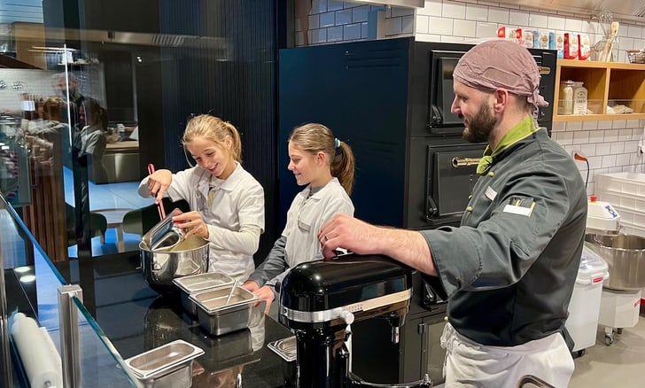 Drei Personen in einer Küche beim Kochen.