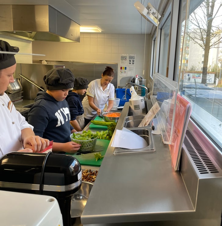 Personen bereiten Essen in einer Küche vor.